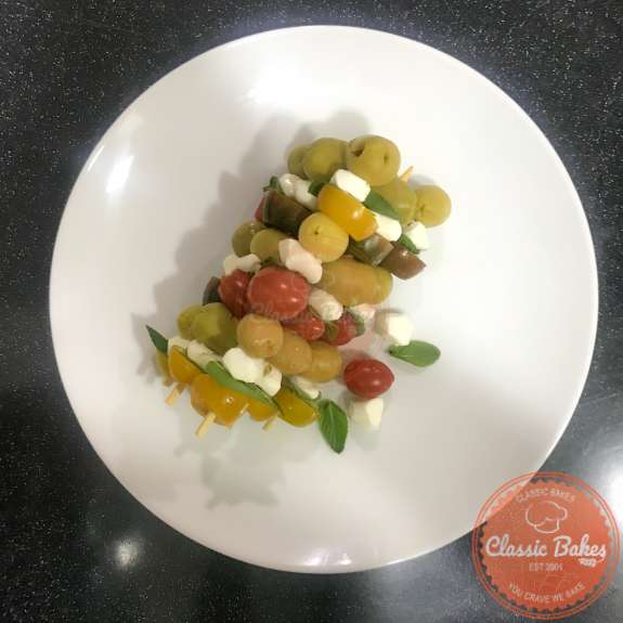 Skewers with tomatoes, basil, mozzarella and olives on a plate. 