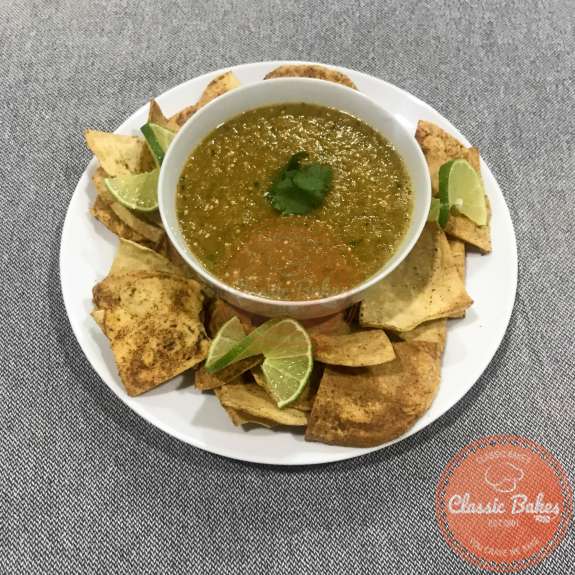 Side View of a bowl of tomatillo red chili salsa and tortilla chips on a plate