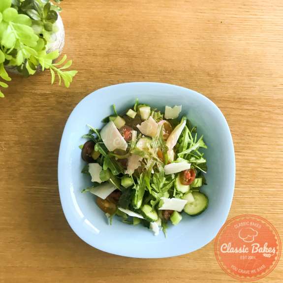 Top view of arugula salad with shaved parmesan in a salad bowl