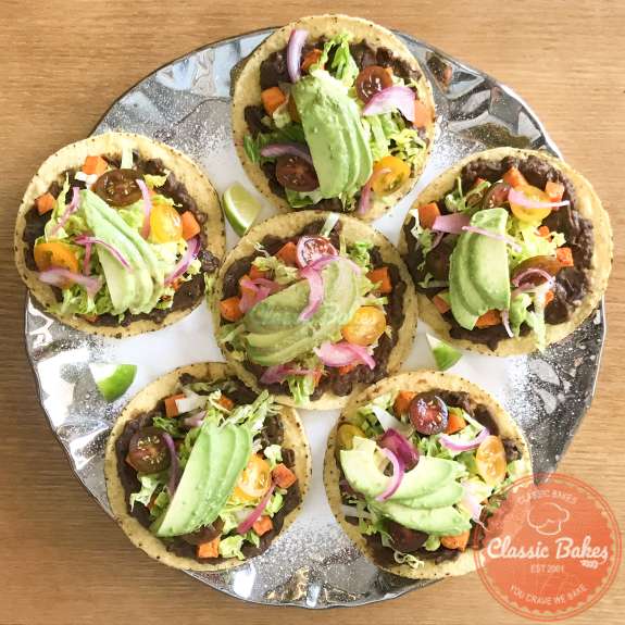 Overview of a platter of six colorful black bean tostadas