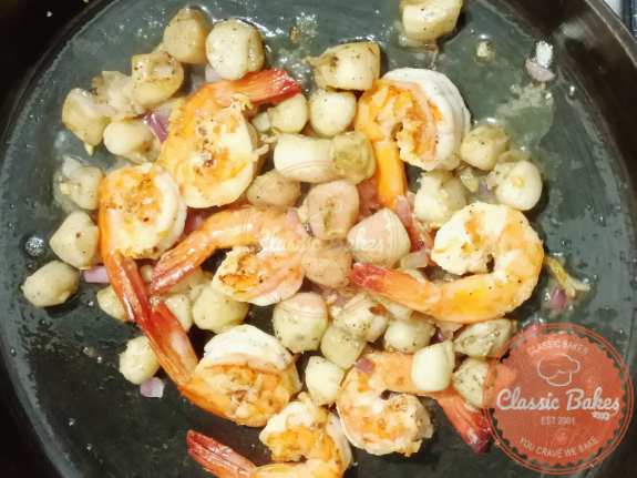 Mixing scallops, shrimp and lemon into the butter