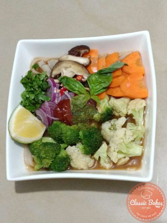Putting vegetables , noodles and broth into a bowl