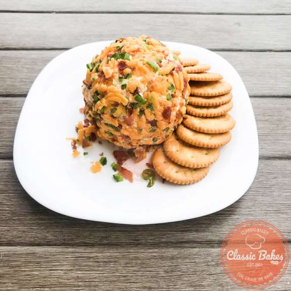 Side shot of a plate with a keto cheese ball with crackers on the side