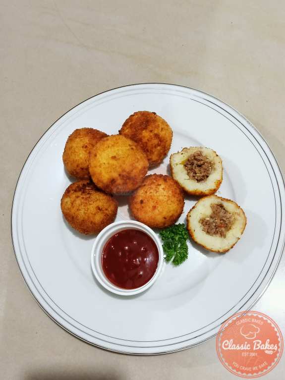 Aerial shot of Stuffed Potato Balls with dip in the middle