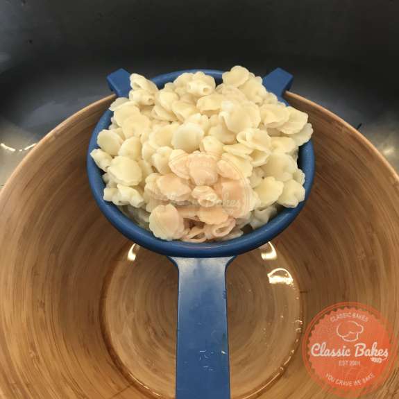 Top view of cooked shell pasta in a strainer over a bowl 