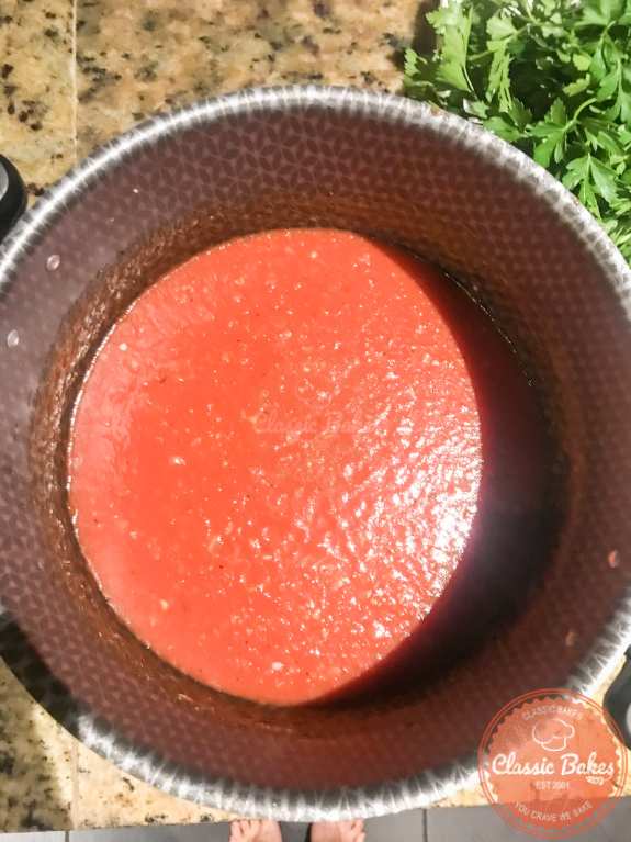 Tomatoes being added to a pot of tomato sauce. 