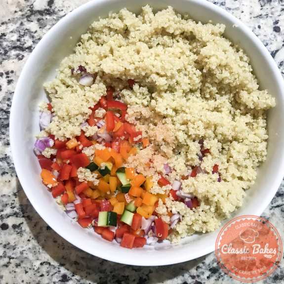 Quinoa and salad ingredients being mixed in a bowl 
