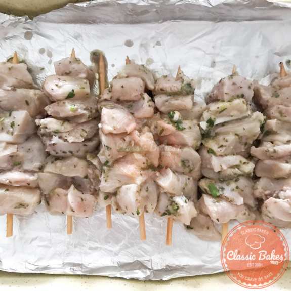 Skewers of chicken on a tray lined with foil 