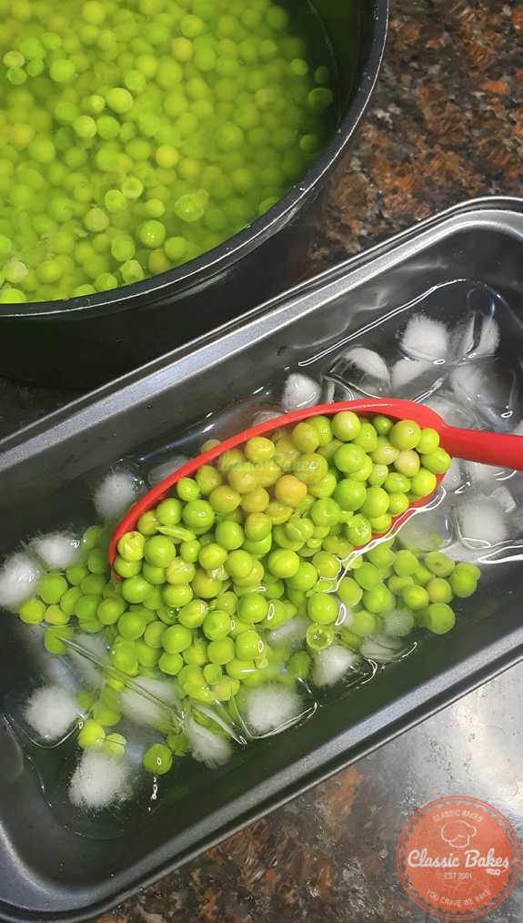 Use a slotted spoon to transfer the peas into the ice water bath, where they will cool for five minutes.