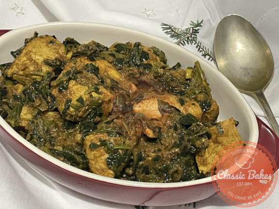 Chicken Saag in a oval plate with spoon on the side