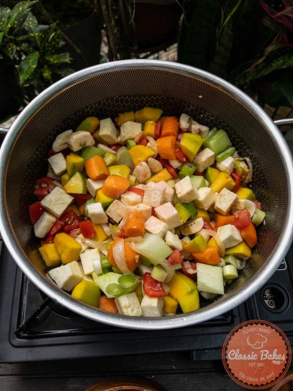 Include the pumpkin, carrots, sweet potatoes, plantains, cho cho, scallions, and tomatoes in the pot. Stir and cook for about 5 minutes, or until the vegetables begin to soften.