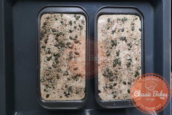 Pumpkin and sesame seeds sprinkled across the mixture in 2 loaf pans