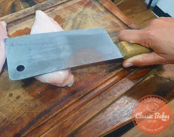  Put a chicken breast on a cutting board and cover it with plastic wrap. Use a meat mallet to flatten the chicken breast until it's uniform in thickness. Transfer the pounded chicken breast to a plate and repeat the process for all the chicken breasts.  If you don't have a mallet, you can use a large kitchen knife to tenderize the chicken.