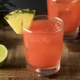 Caribbean Rum Punch in a short glass with fresh lime and pineapple cut