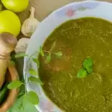 Aerial shot of Cilantro Chutney in a bowl with ingredients on the side