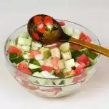 Cucumber Tomato Salad in a bowl with serving spoon