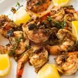 Close up shot of Jerk shrimps in a plate with lemons on the side