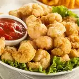 Front shot of Popcorn Shrimp in plate with dip and lettuce on the side