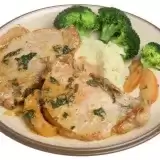 Front shot of Slow Cooker Pork Chops and Gravy in a plate with sides