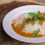 Front shot of Coconut Curry Soup with rice noodles in a plate with garnish on top