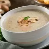 Front shot of Cream of Mushroom Soup in a bowl with spoon on the side
