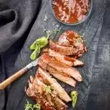 Aerial shot of sliced Air Fryer Flank Steak with sauce and garnish