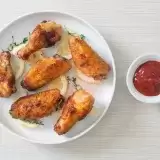 Aerial shot of Fried lemon pepper chicken wings in a plate with ketchup on the side