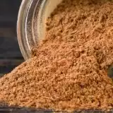 Close up shot of spilled Jerk Seasoning Paste in a jar on a wood background