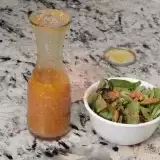 Front shot of Carrot Ginger Dressing with salad on the side