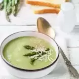 Front shot of Cream of Asparagus Soup in a bowl with spoon on the side