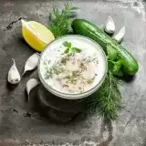 Aerial shot of Vegan Tzatziki in a bowl with ingredients on the side