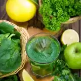 Arial view of a glass of Green Goddess Smoothie with vegetables on the side