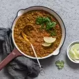 Aerial shot of Vegan Coconut Lentil Curry in a pan with lime on the side