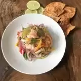 Side View of shrimp ceviche on a place with tortilla chips and slices of lime