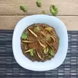 Overview of a bowl of refried beans garnished with scallions and tortilla chips